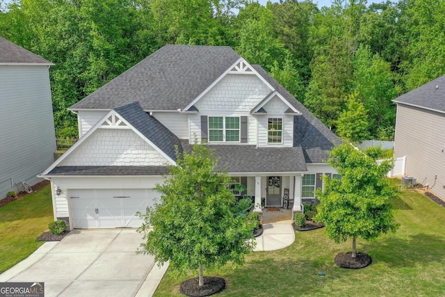 craftsman inspired home featuring concrete driveway, an attached garage, a shingled roof, and covered porch