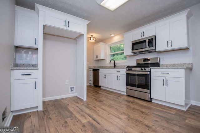 6213 Cherry Ln, Douglasville, GA 30134 - kitchen featuring appliances with stainless steel finishes, white cabinets, tasteful backsplash, wood finished floors, and baseboards