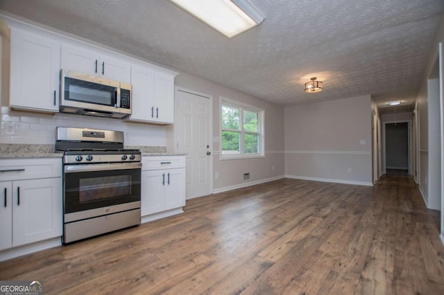6213 Cherry Ln, Douglasville, GA 30134 - kitchen featuring appliances with stainless steel finishes, a textured ceiling, dark wood-style floors, white cabinetry, and baseboards