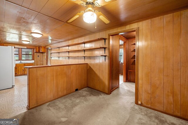 3011 Refuge Rd, Jasper, GA 30143 - kitchen with a peninsula, brown cabinets, freestanding refrigerator, light carpet, and wooden walls