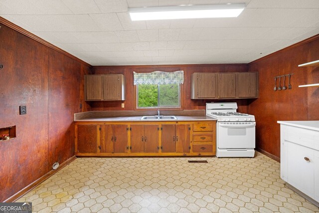 3011 Refuge Rd, Jasper, GA 30143 - kitchen featuring white range with gas stovetop, wood walls, baseboards, and a sink