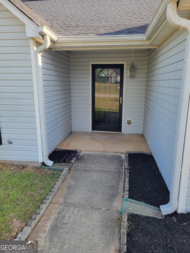 doorway to property featuring a shingled roof