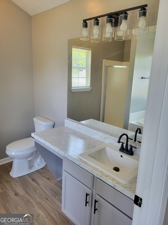 full bath with vanity, a stall shower, wood finished floors, and toilet