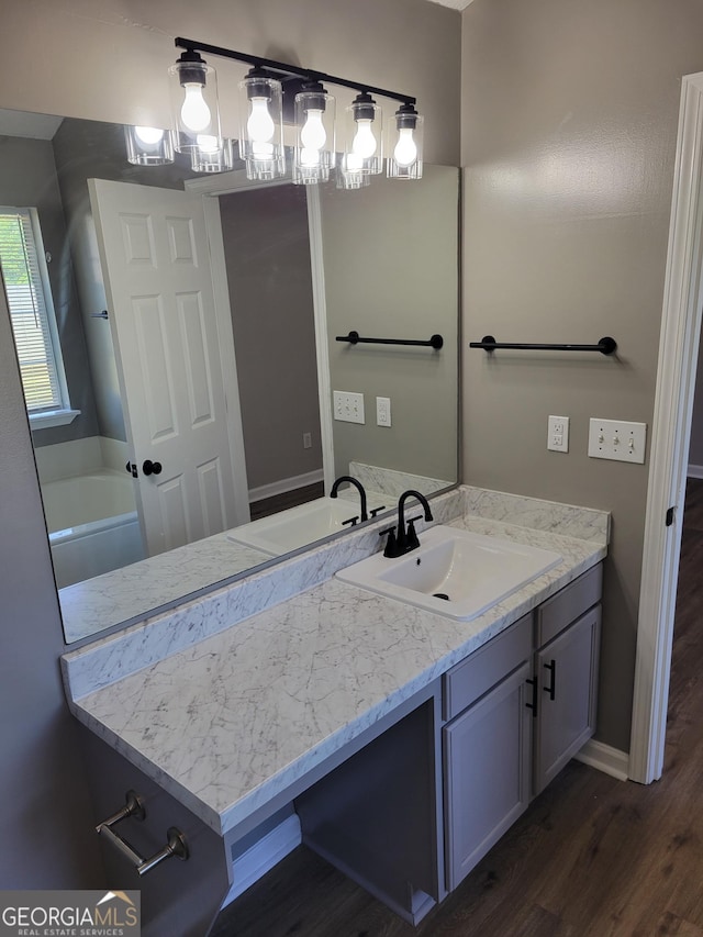full bathroom featuring vanity, baseboards, wood finished floors, and a tub