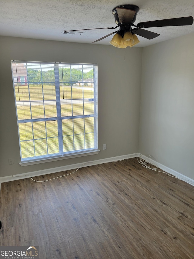 unfurnished room with a ceiling fan, baseboards, wood finished floors, and a textured ceiling