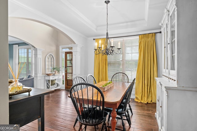 dining area featuring arched walkways, ornate columns, a chandelier, dark wood-style floors, and ornamental molding