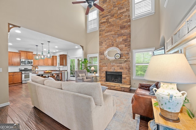 living area featuring a towering ceiling, healthy amount of natural light, dark wood-style floors, ceiling fan, and recessed lighting