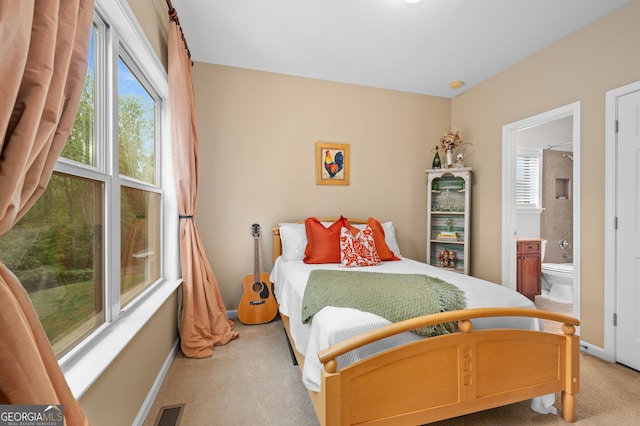 bedroom with light carpet, ensuite bathroom, visible vents, and multiple windows