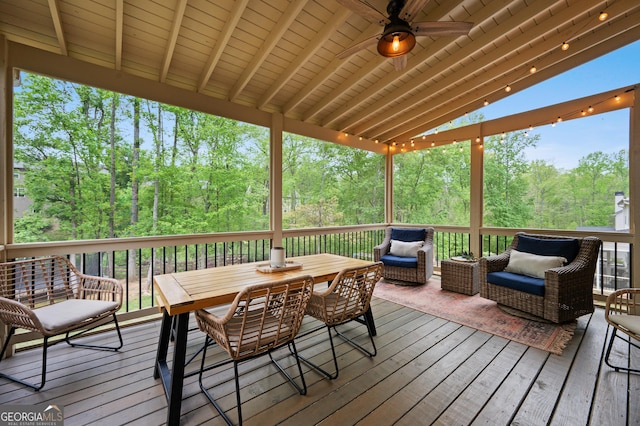 wooden deck featuring ceiling fan, outdoor dining area, and a wooded view
