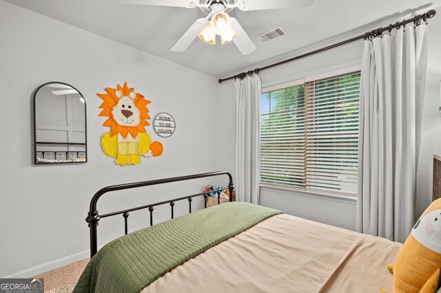 carpeted bedroom with visible vents, baseboards, and a ceiling fan