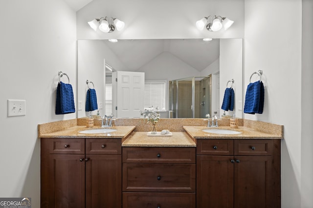 full bath with a sink, double vanity, lofted ceiling, and a shower stall