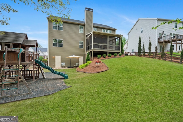 rear view of house with a chimney, a yard, a sunroom, and fence