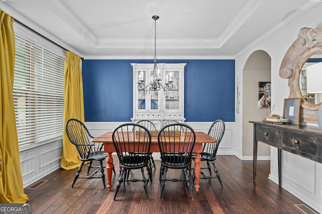dining space featuring a decorative wall, a wainscoted wall, a chandelier, wood-type flooring, and a tray ceiling
