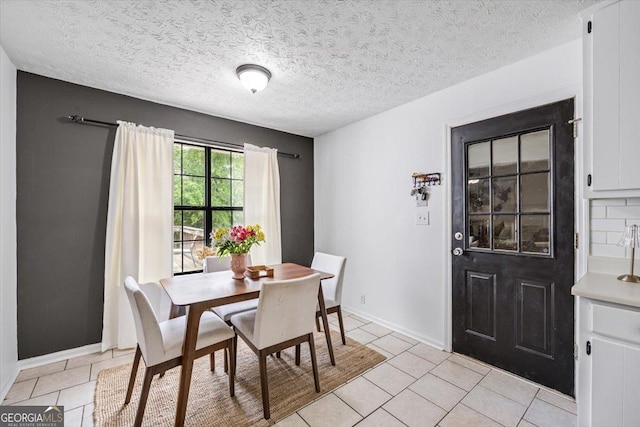 dining area featuring light tile patterned flooring, a textured ceiling, and baseboards