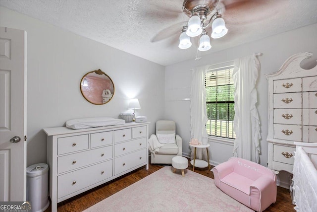 bedroom with ceiling fan, dark wood finished floors, and a textured ceiling