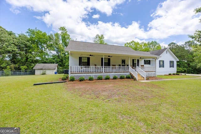 view of front of house featuring ceiling fan, fence, a front yard, a porch, and an outbuilding