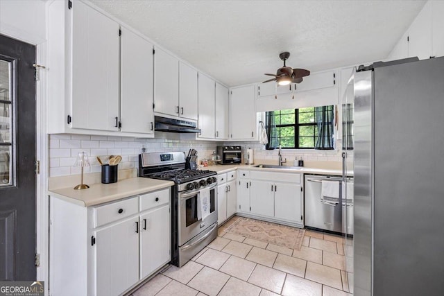 kitchen featuring ceiling fan, appliances with stainless steel finishes, a sink, backsplash, and under cabinet range hood