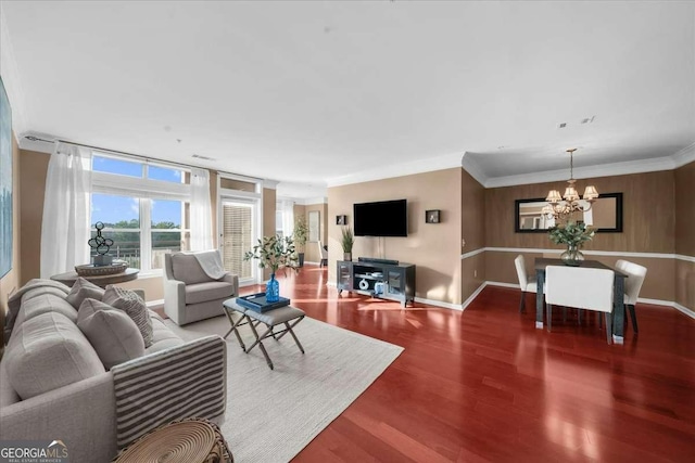 living area featuring baseboards, crown molding, wood finished floors, and a chandelier