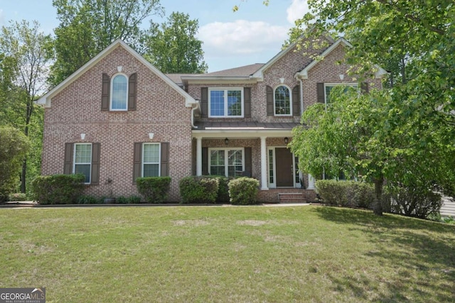 view of front of home with a front yard, a porch, and brick siding