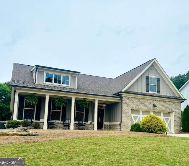 craftsman house with board and batten siding, brick siding, a front yard, and a porch