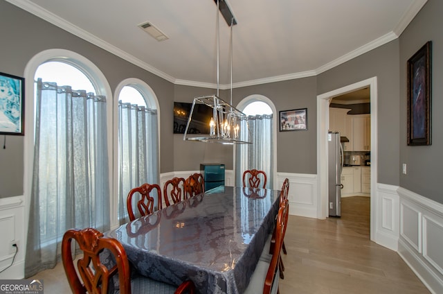 dining area featuring crown molding, plenty of natural light, and wood finished floors