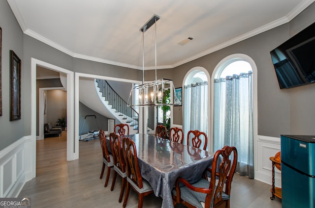 dining space with crown molding, a notable chandelier, stairs, wood finished floors, and visible vents