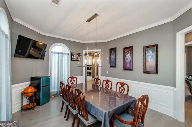 dining area featuring crown molding, visible vents, and wood finished floors