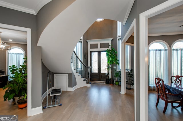 entryway featuring french doors, ornamental molding, stairs, and wood finished floors