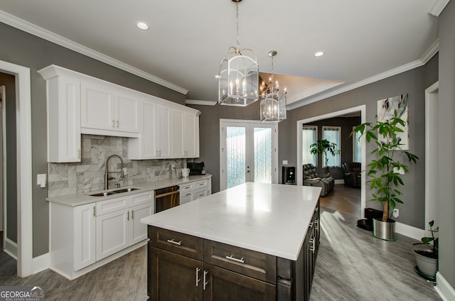kitchen featuring an inviting chandelier, a sink, white cabinetry, and light countertops
