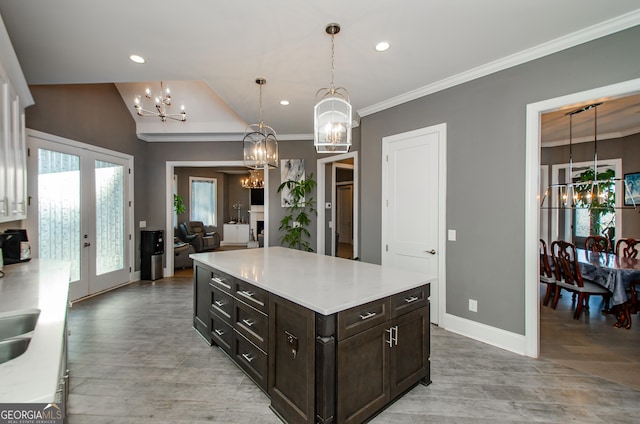 kitchen with light wood-style floors, light countertops, dark brown cabinets, and a notable chandelier