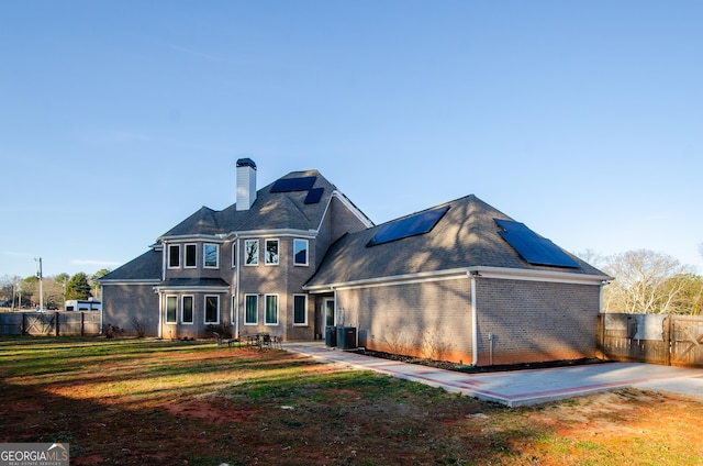 back of property featuring a fenced backyard, a patio, a chimney, and roof mounted solar panels