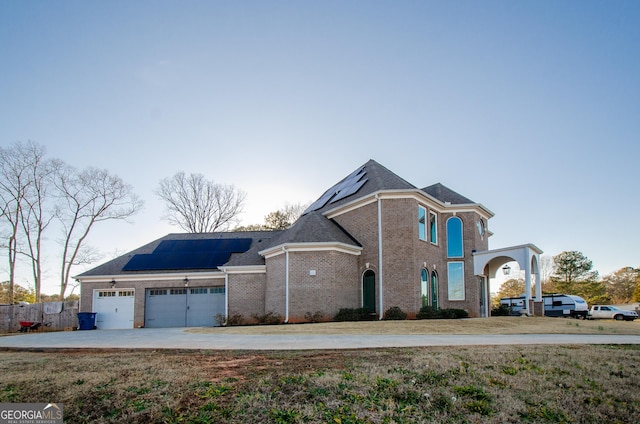 traditional-style home with a garage, concrete driveway, solar panels, and brick siding