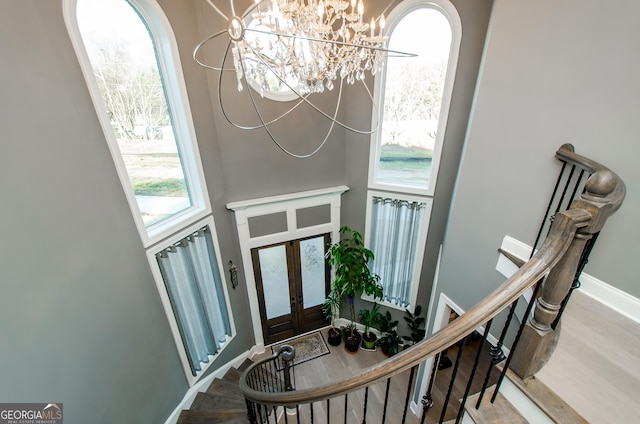 foyer with a chandelier, french doors, baseboards, wood finished floors, and stairway
