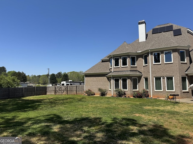 back of property featuring a lawn, a fenced backyard, and brick siding
