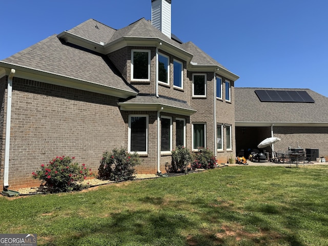 rear view of property featuring roof mounted solar panels, a patio, and brick siding