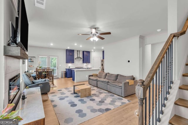 3493 Monarch Ave, Duluth, GA 30096 - living area featuring a fireplace, stairs, a ceiling fan, light wood-type flooring, and visible vents