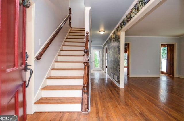 stairway with wood-type flooring, baseboards, and ornamental molding