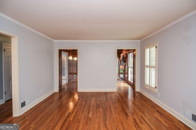 empty room with visible vents, ornamental molding, baseboards, and wood finished floors