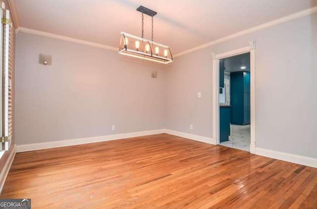 unfurnished room featuring light wood-type flooring, ornamental molding, baseboards, and an inviting chandelier