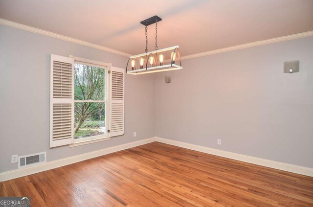 unfurnished room with visible vents, baseboards, crown molding, and wood finished floors