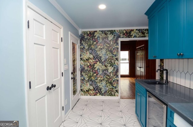 kitchen with blue cabinetry, dark countertops, a sink, wine cooler, and wallpapered walls