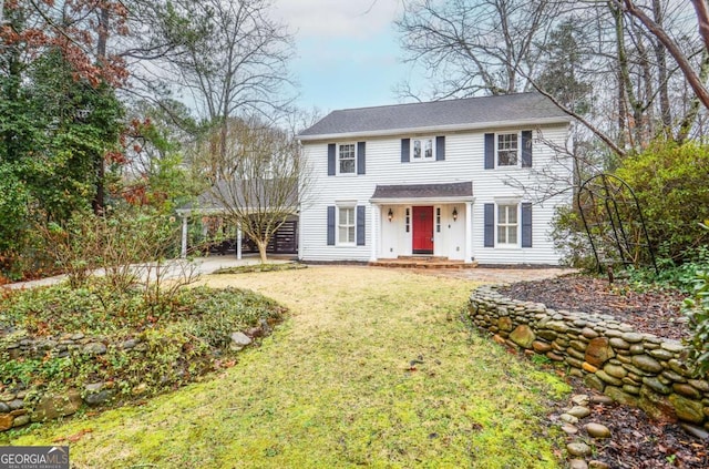 colonial inspired home featuring a carport and a front lawn