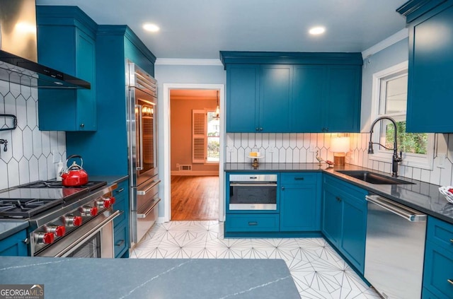 kitchen featuring ornamental molding, high end appliances, a healthy amount of sunlight, wall chimney exhaust hood, and a sink