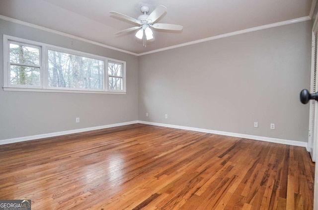 empty room featuring wood-type flooring, a ceiling fan, baseboards, and ornamental molding