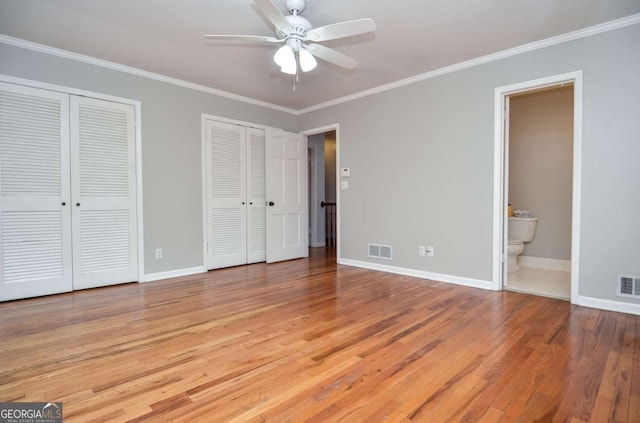 unfurnished bedroom with two closets, baseboards, visible vents, and ornamental molding