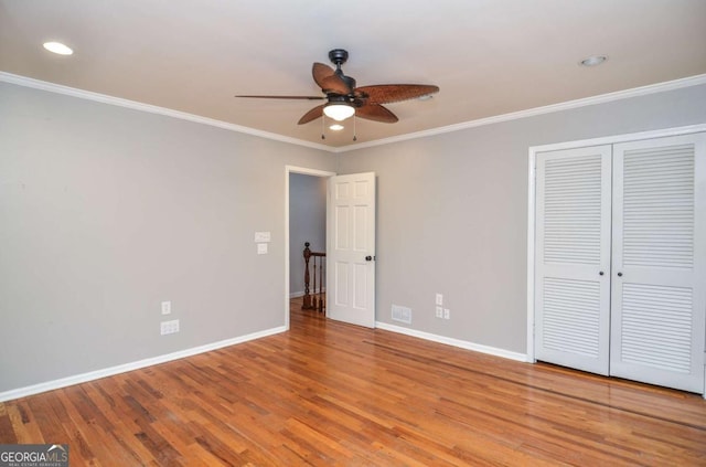 unfurnished bedroom with crown molding, recessed lighting, baseboards, wood finished floors, and a closet