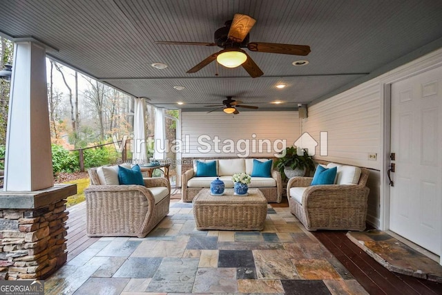 sunroom / solarium featuring a ceiling fan, a wall of windows, recessed lighting, and an outdoor hangout area