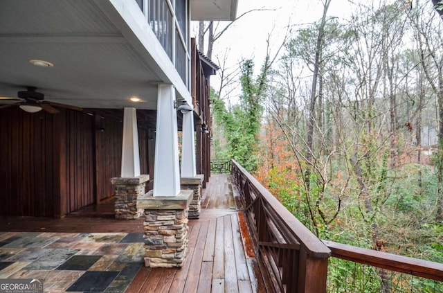 wooden terrace featuring a wooded view and a ceiling fan