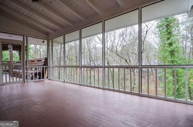 unfurnished sunroom with a view of trees and beam ceiling