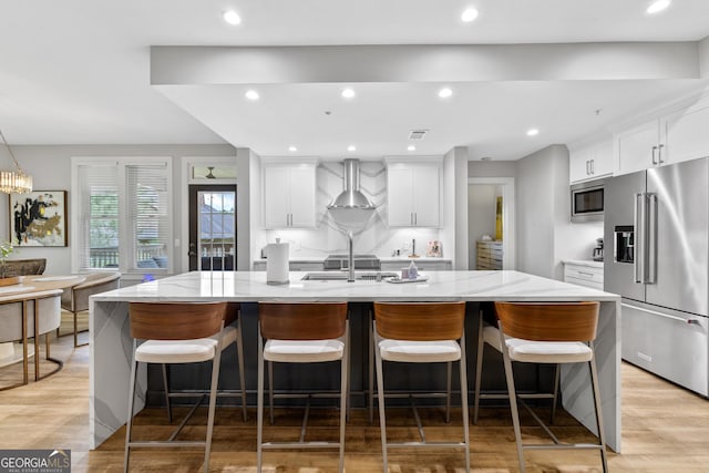 1010F Tailwater, Greensboro, GA 30642 - kitchen with wall chimney range hood, stainless steel appliances, a large island, and white cabinets